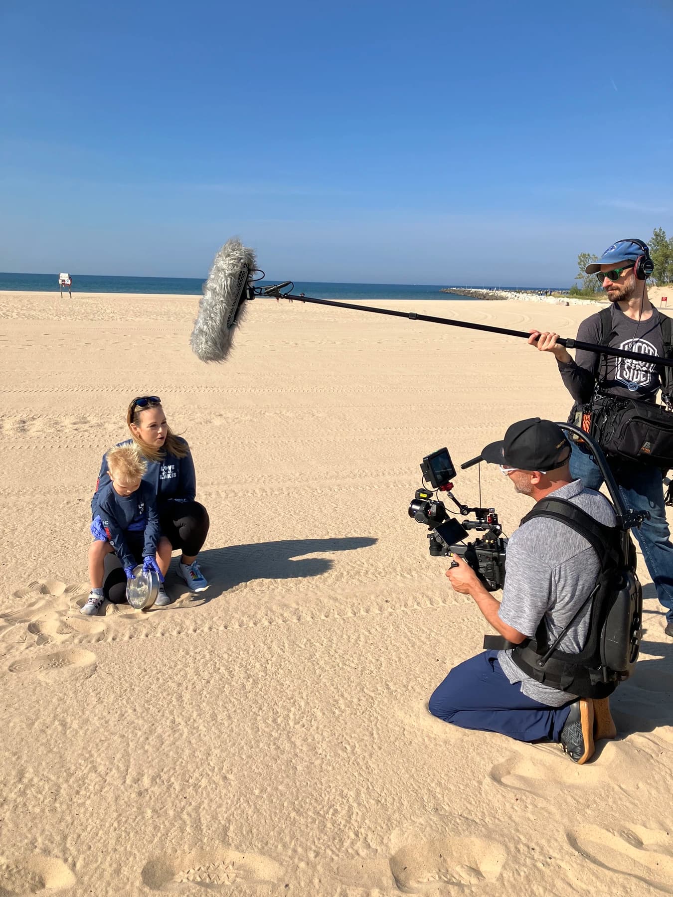 SALT crew filming a parent and child filtering beach sand for micro-plastics during the Unilever and Meijer cleanup.
