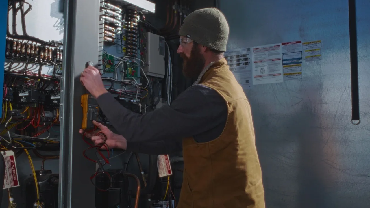 Grand Valley Automation technician checks wiring and diagnostics inside a controls panel.