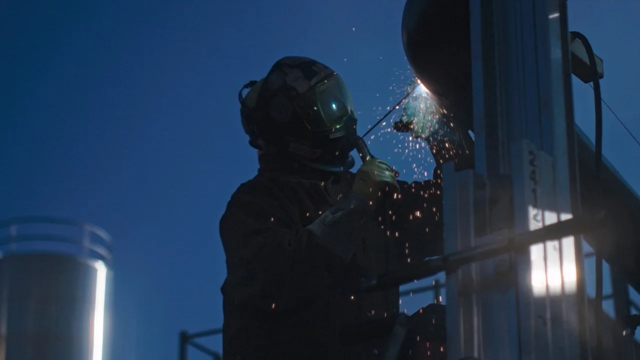 Worker welds with sparks flying before sunrise during the VDM and GVA recruitment campaign.