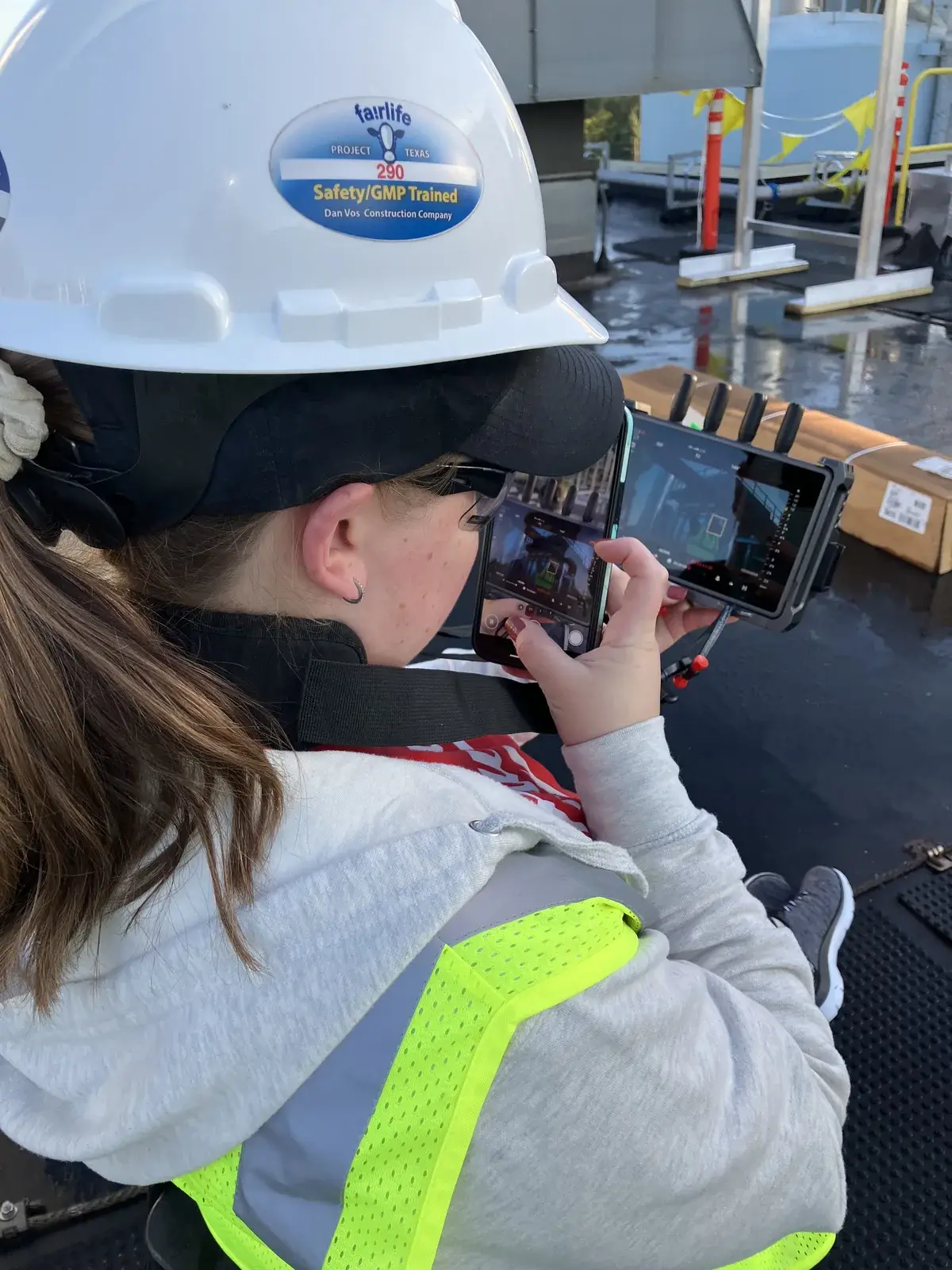 Client in safety gear reviews live camera playback on an industrial rooftop during the VDM and GVA recruitment campaign.