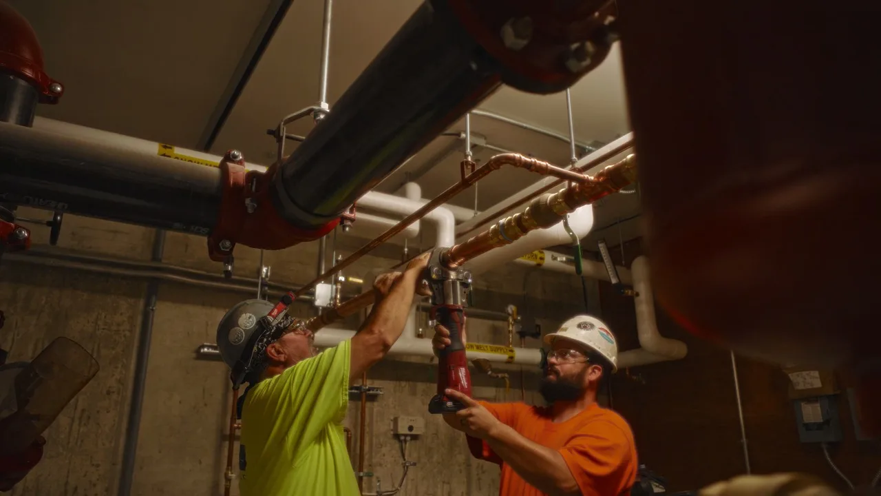 Two Van Dyken Mechanical workers install copper piping together on a jobsite in Grandville, Michigan.